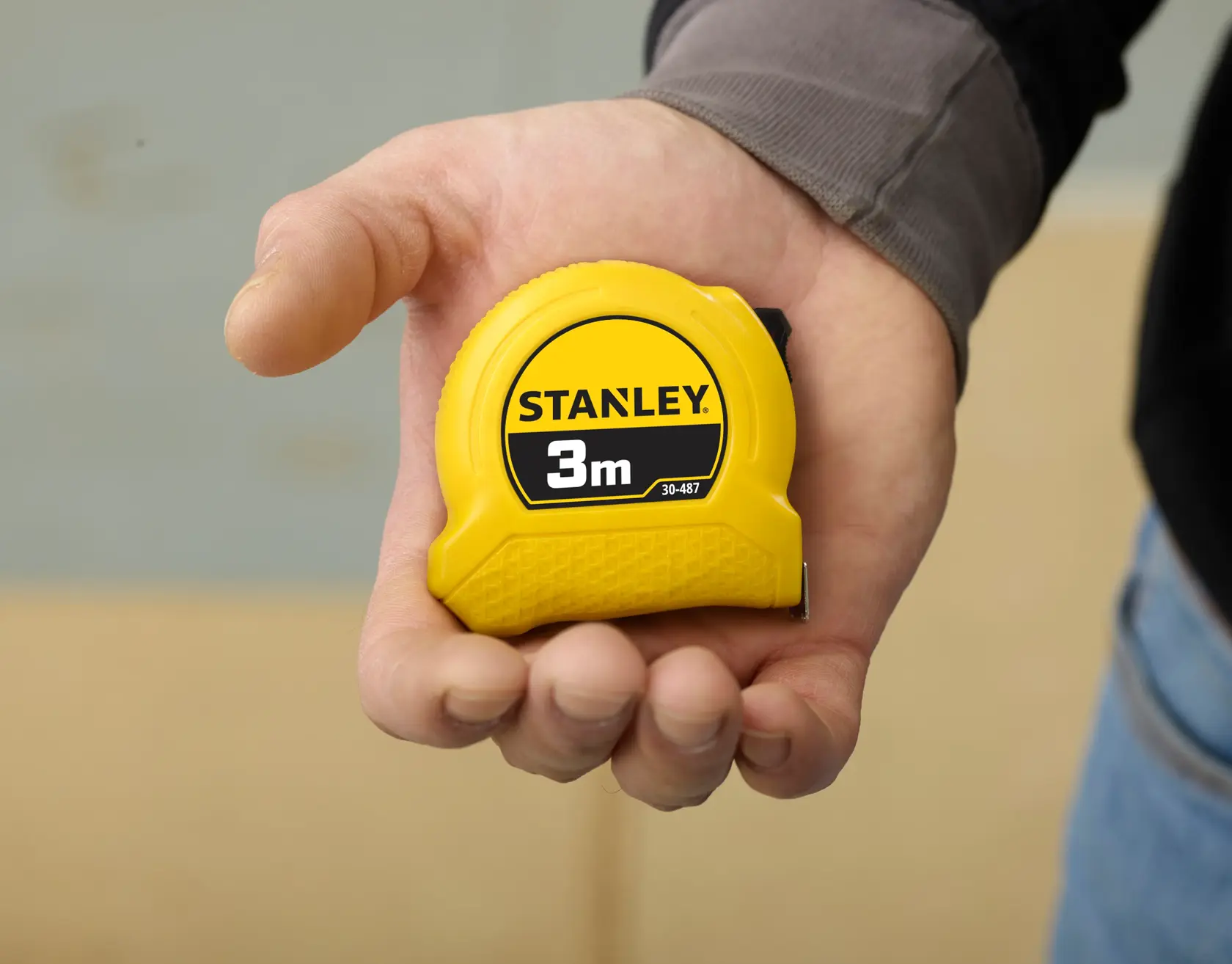 STANLEY 0-30-487 gelbes 3m Maßband in der Hand gehalten, Markenlogo deutlich sichtbar.