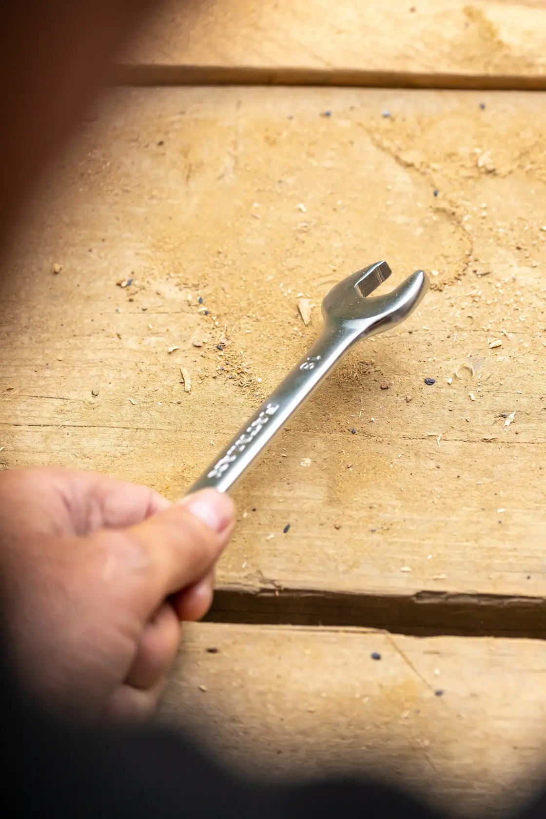 STANLEY FMMT13030-0 wrench held in hand on wooden surface, close-up photography.