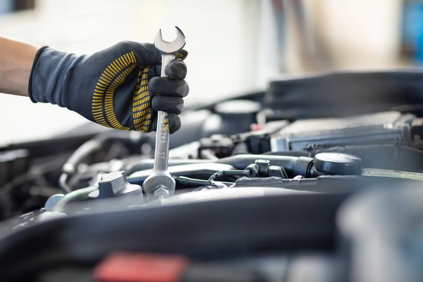 Photo of STANLEY FMMT13071-0 wrench held by gloved hand working on car engine, close-up view.
