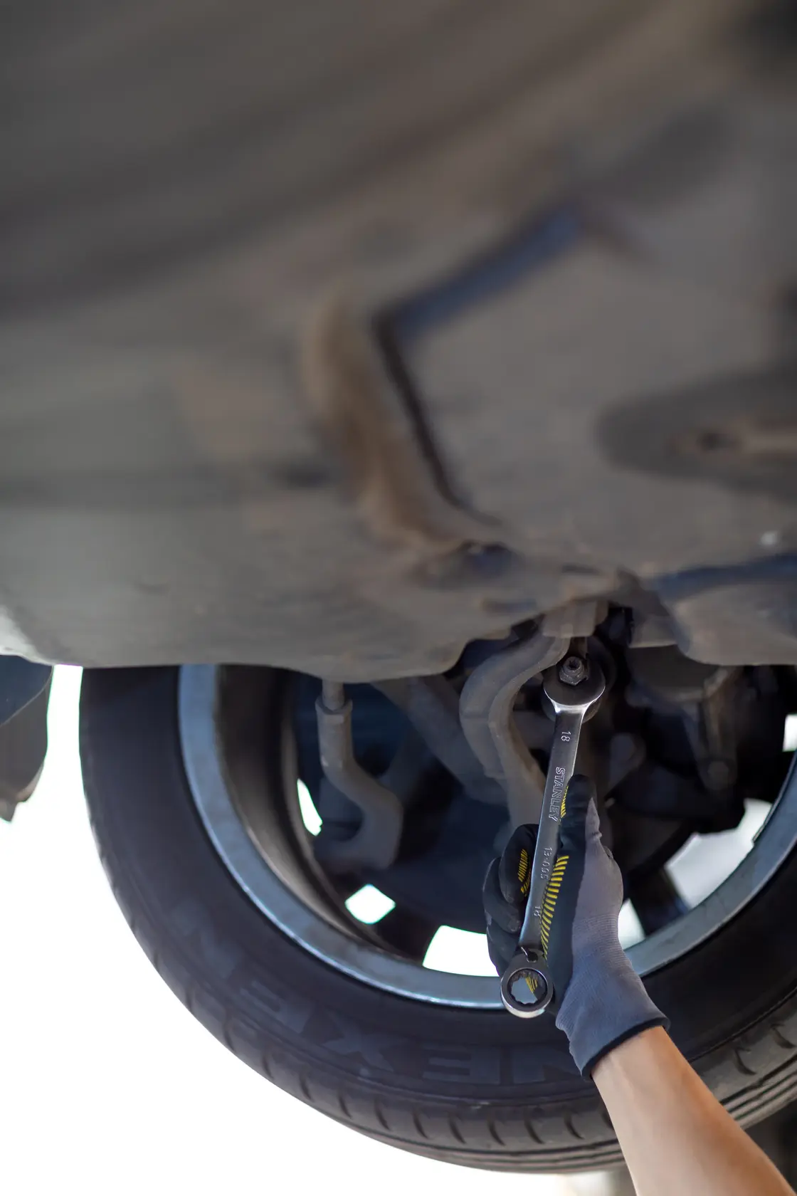 STANLEY FMMT13083-0 ratchet wrench in use on car wheel, automotive maintenance scene.