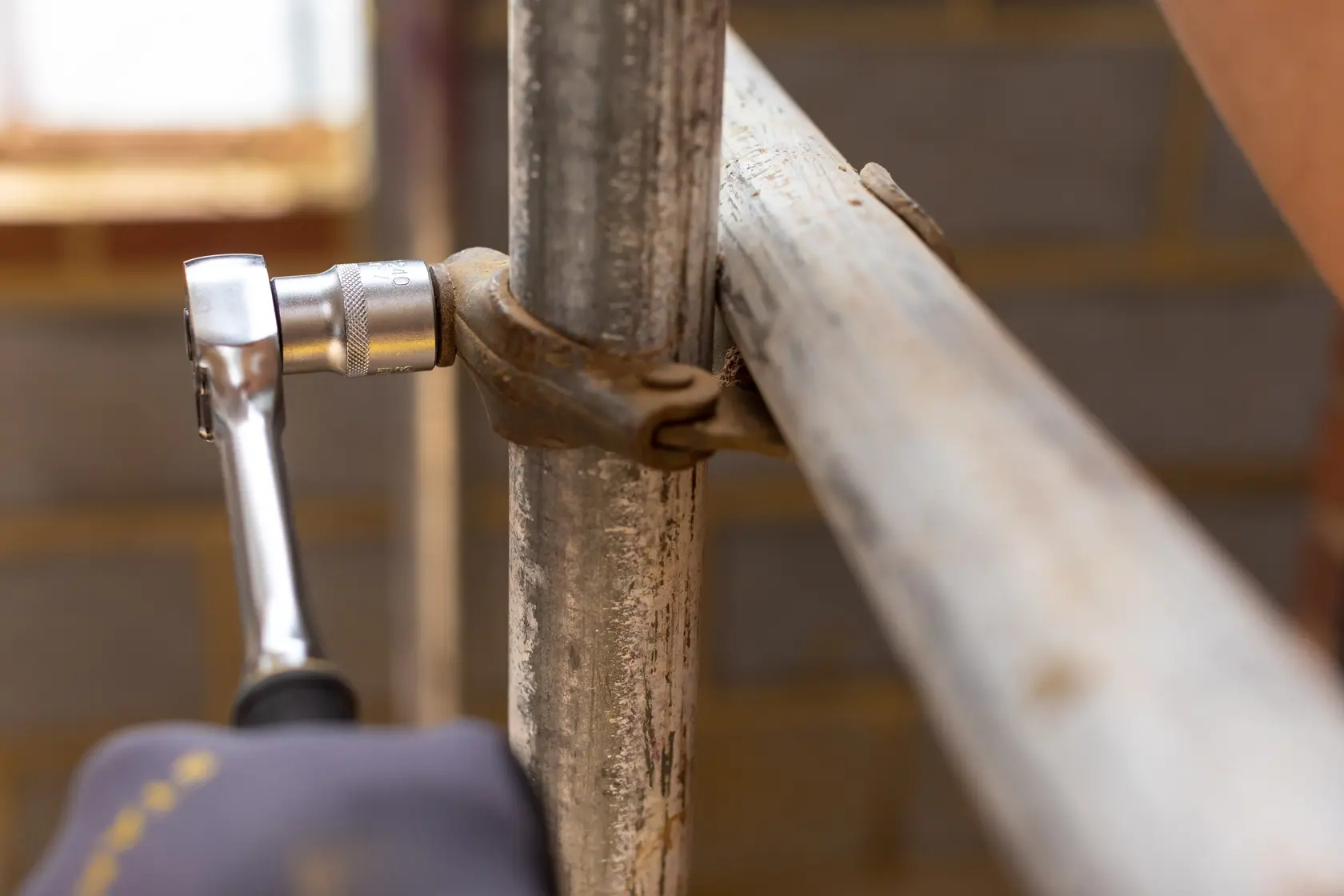 STANLEY FMMT17244-0 ratchet tool tightening a scaffolding clamp, close-up photography.