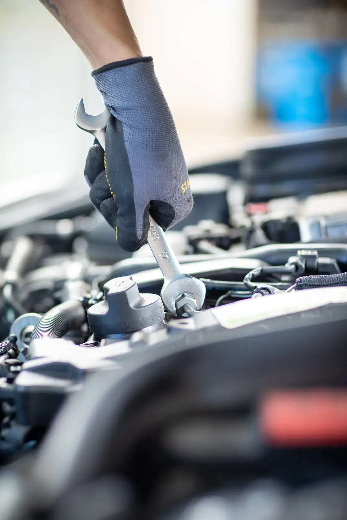 Photo of a gloved hand using a STANLEY FMMT82901-0 wrench to tighten a bolt in a car engine bay.