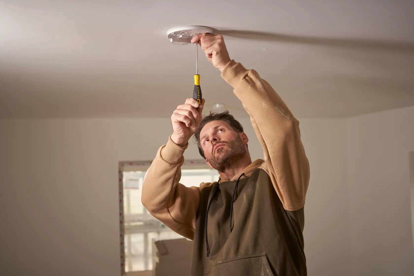 STANLEY STHT0-60276 screwdriver used to install ceiling fixture, indoor setting, product in use.