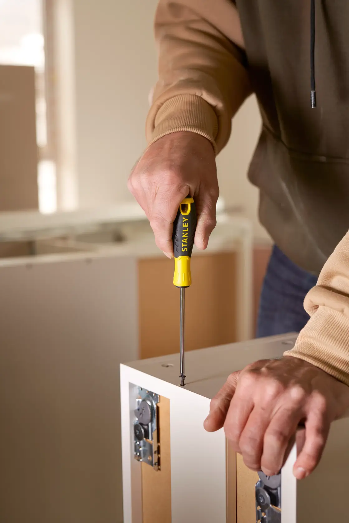 Stanley STHT0-60276 screwdriver used on cabinet, close-up photography, yellow and black handle.