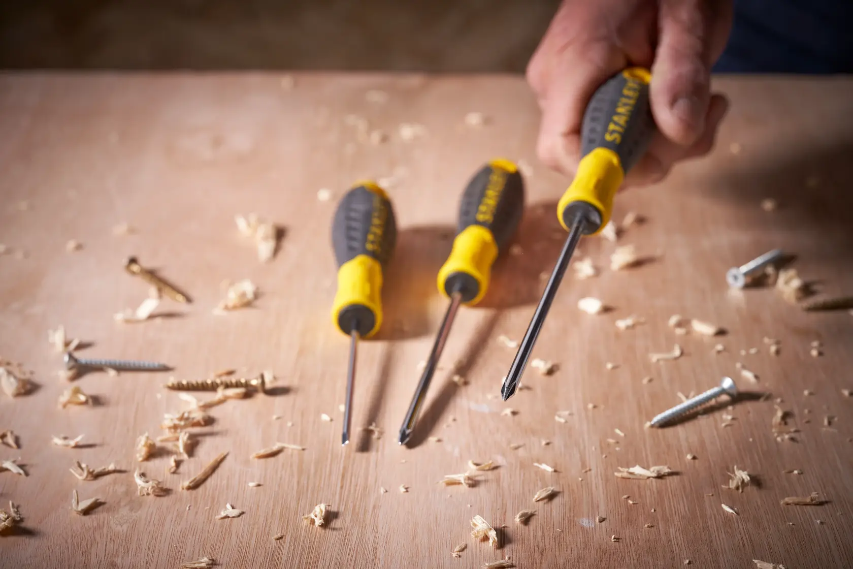 STANLEY STHT0-60335 screwdriver set with black and yellow handles on wood with screws and shavings.