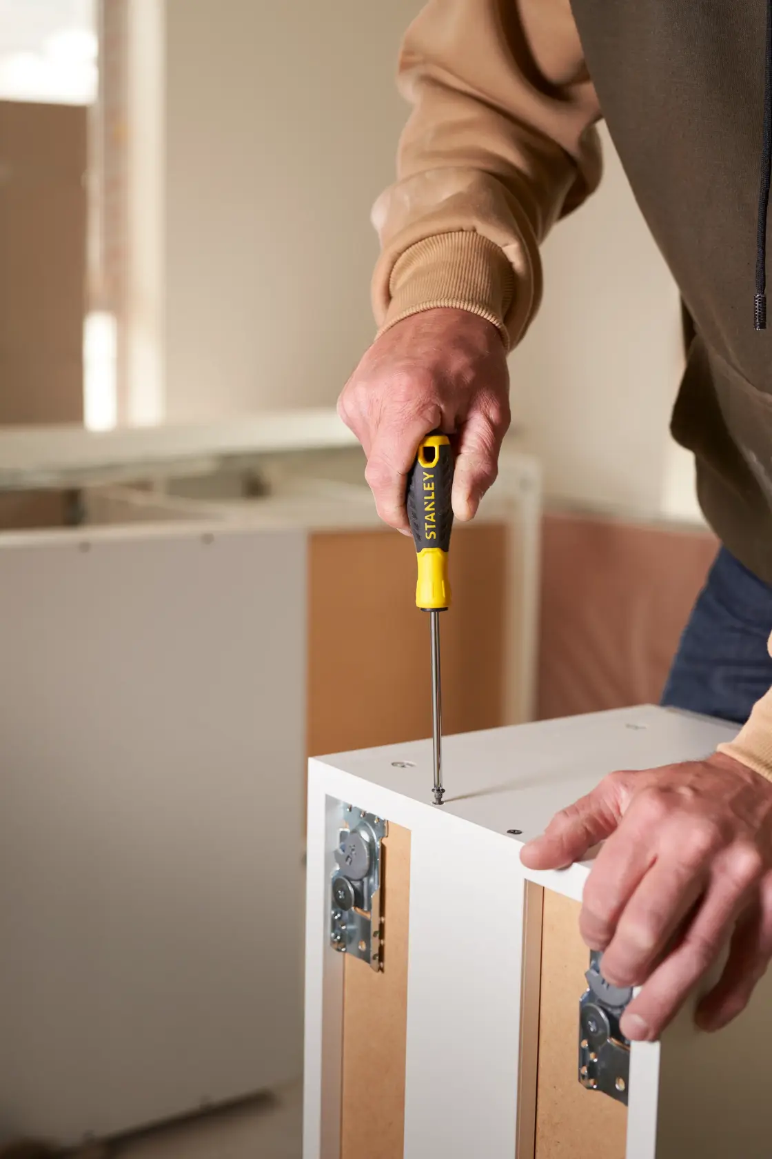 STANLEY STHT0-60335 screwdriver used on white furniture, close-up photo of tool in action.