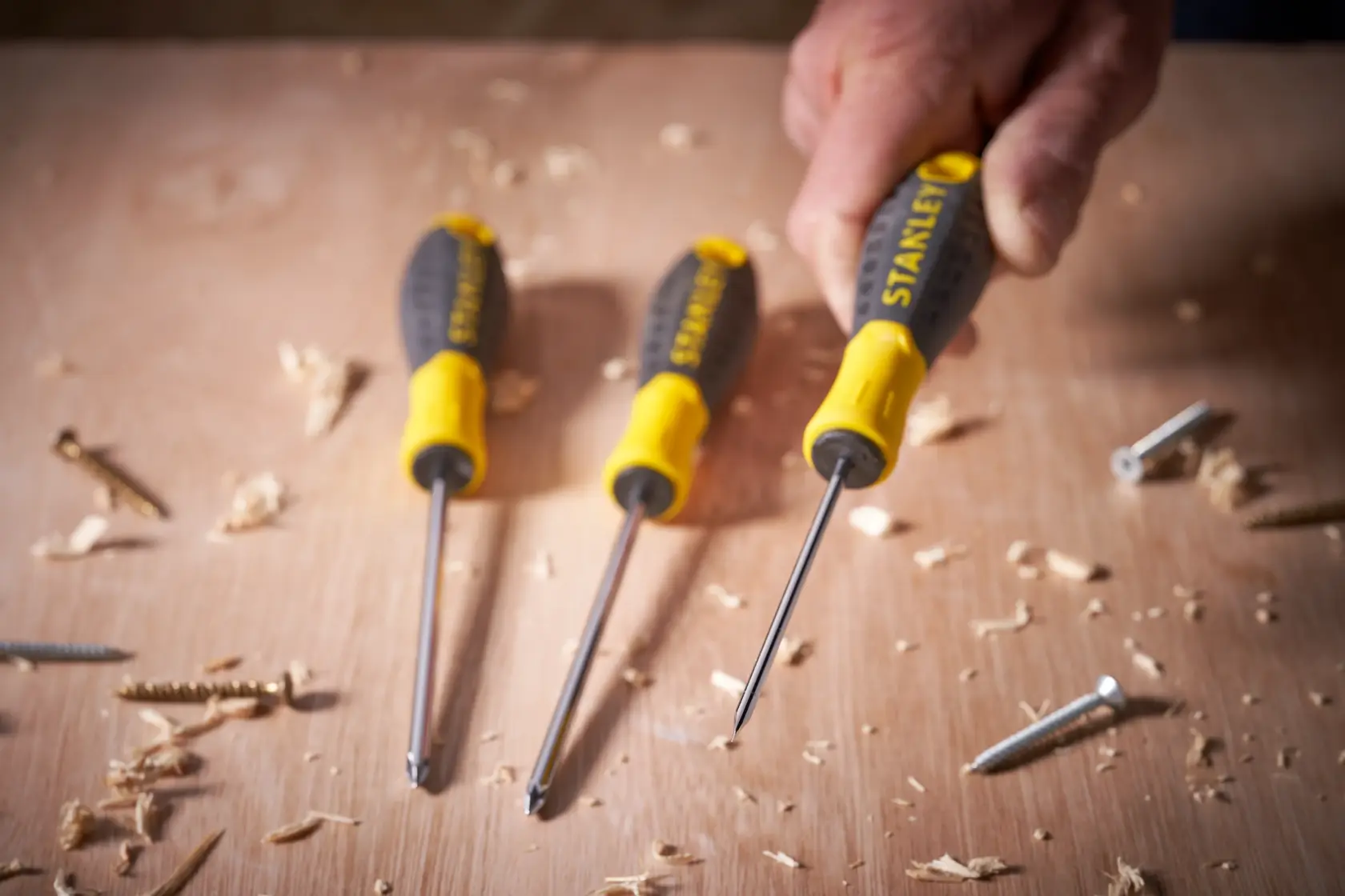 STANLEY STHT0-60358 screwdriver set with yellow and black handles on a wood surface with screws and shavings.