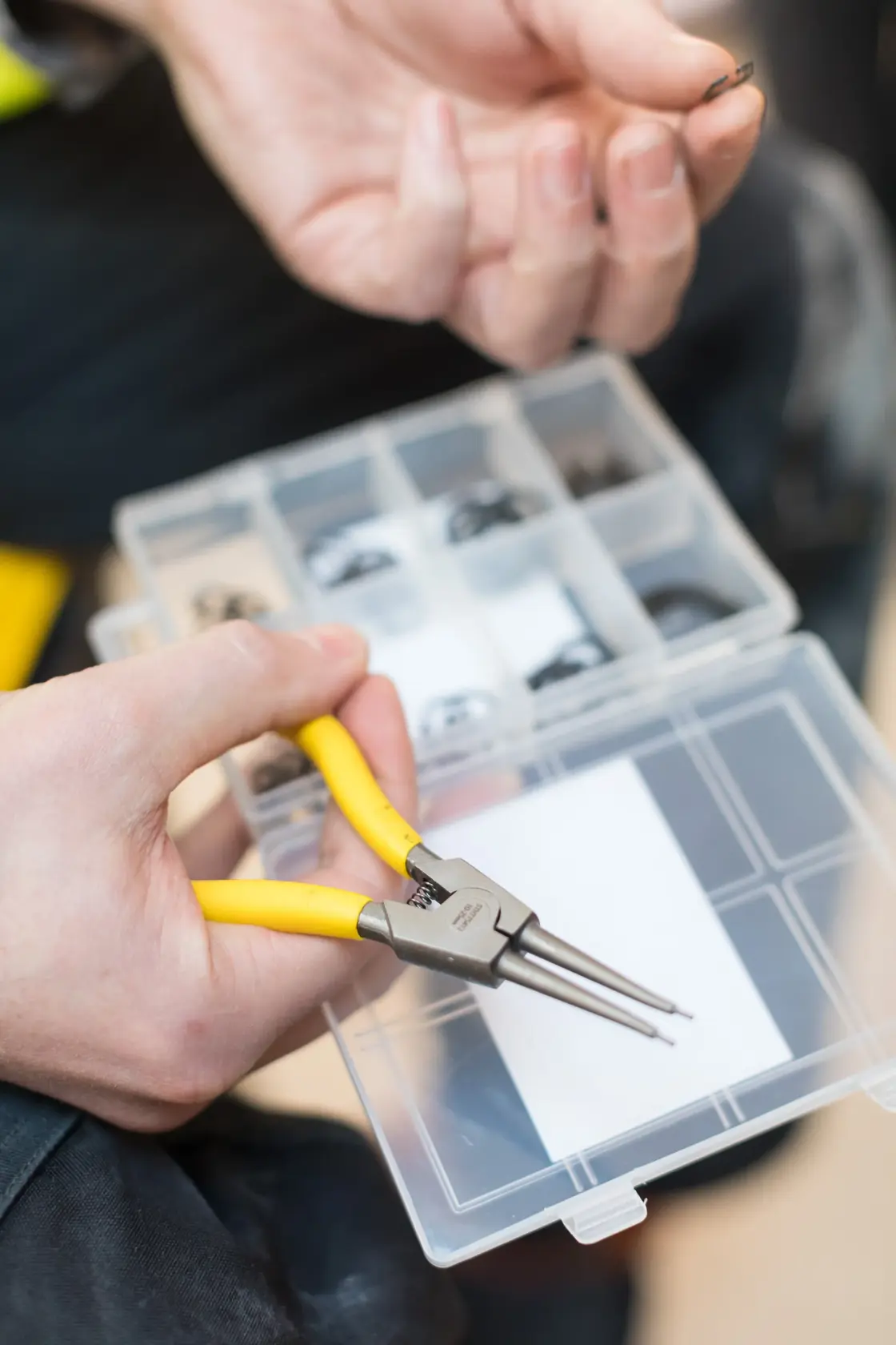 STANLEY STHT0-75412 snap ring pliers with yellow handles held above organizer box, close-up view.