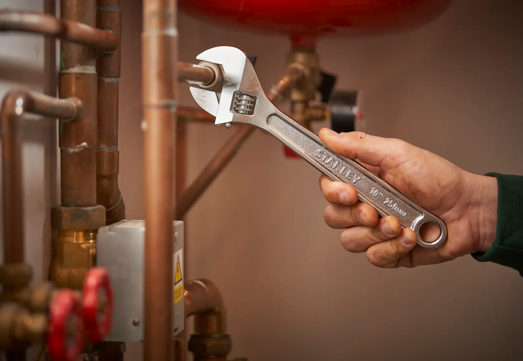 Stanley STHT13156-0 adjustable wrench used on copper pipes, close-up of tool in hand.