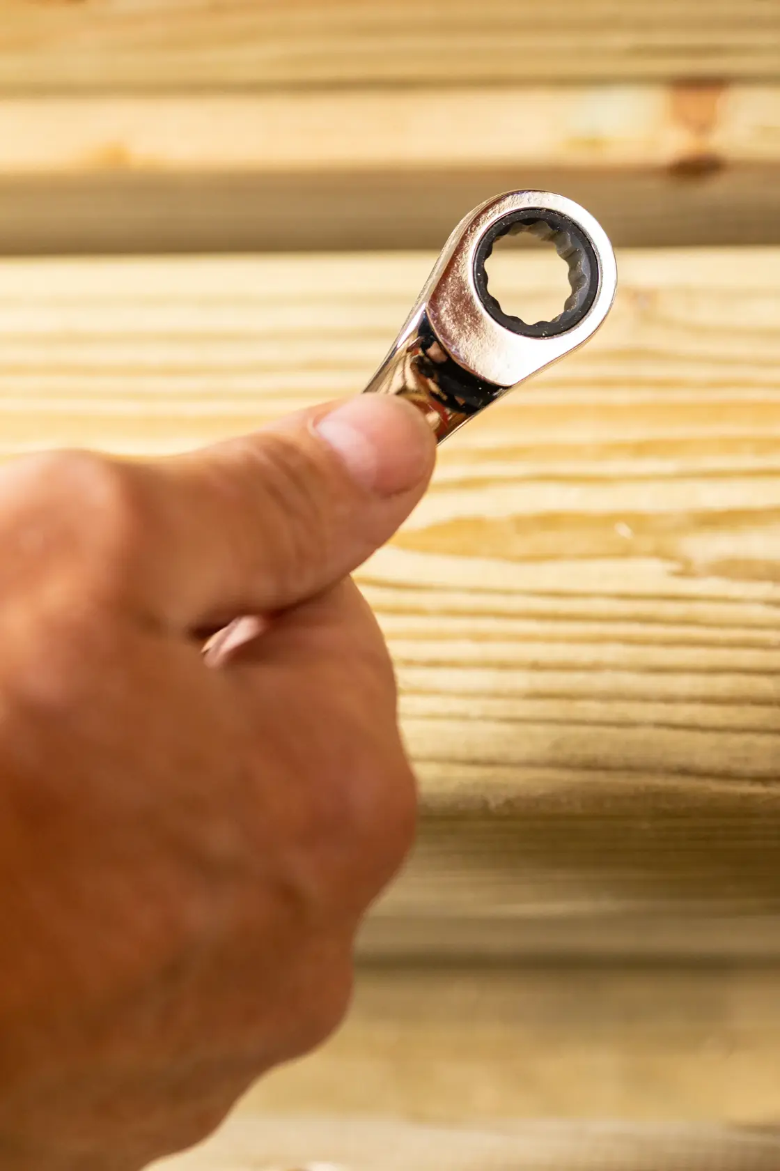 STANLEY STMT89912-0 ratcheting wrench held in hand, close-up view against wooden background.