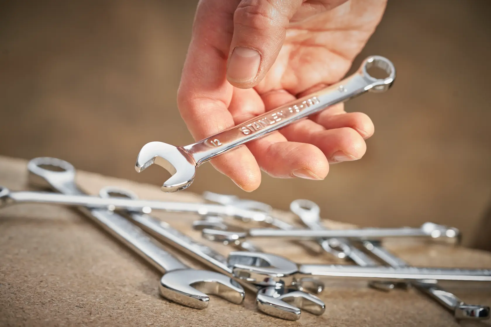 Photo of STANLEY STMT95911-0 wrench held in hand, with other chrome wrenches on a work surface.